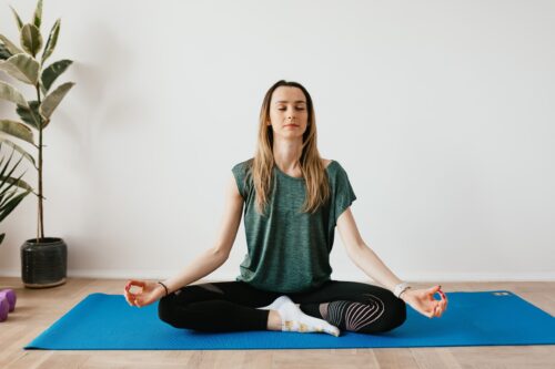 woman sitting peacefully in a yoga pose meditating on a mat